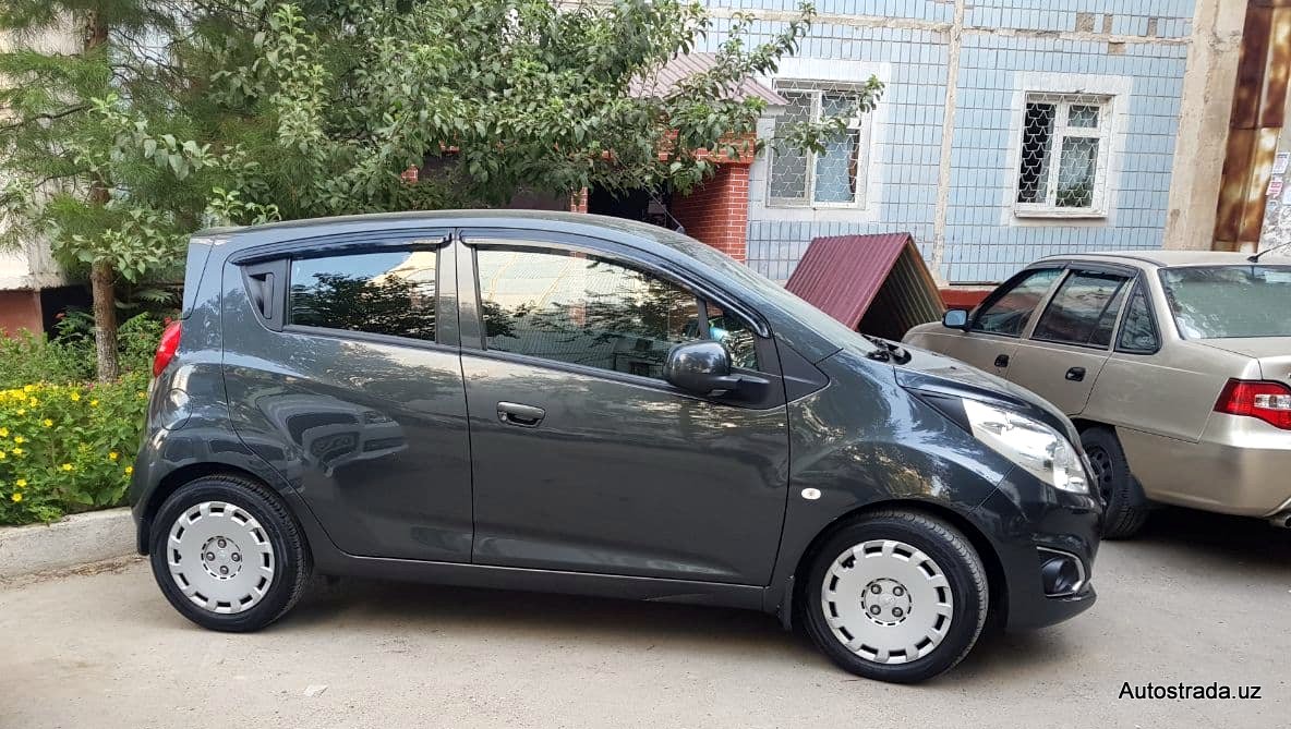 Chevrolet Spark припаркованный на стоянке во дворе многоквартирного дома в Ташкенте.