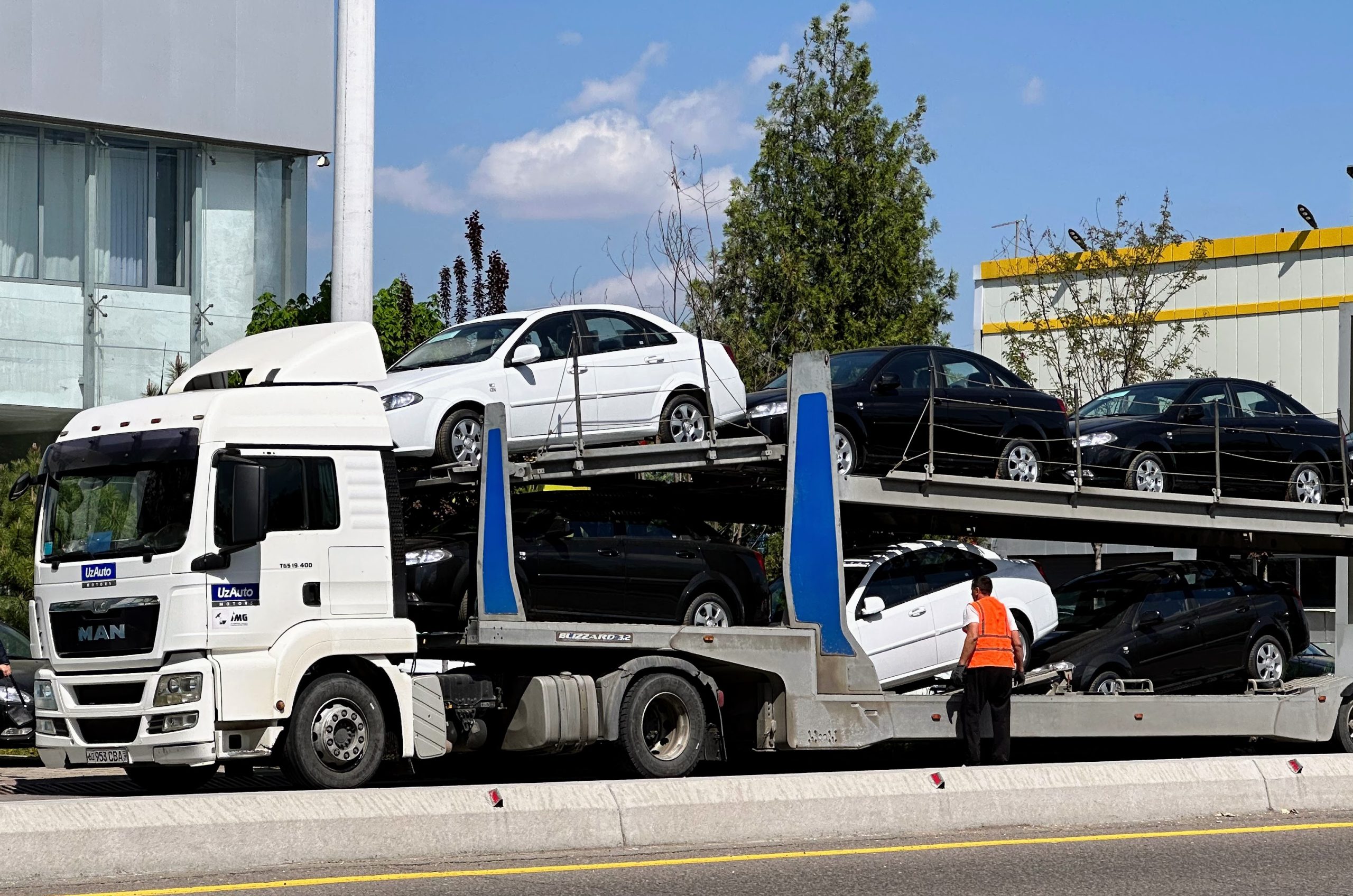 Трейлер с автомобилями Chevrolet Lacetti разргужается у автосалона UzAuto Motors в Ташкенте