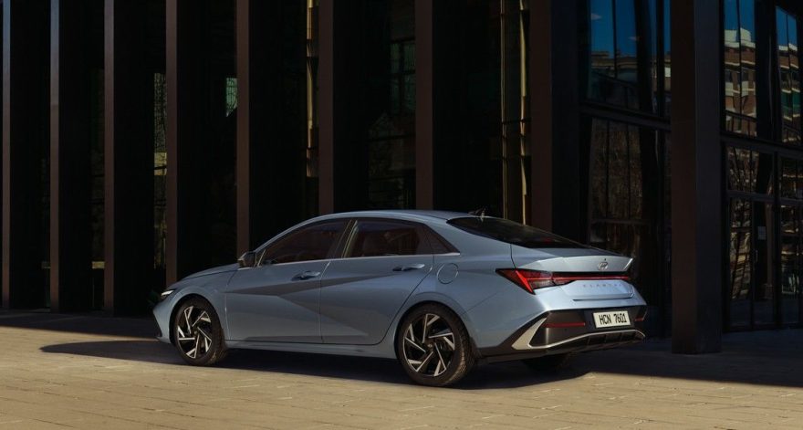 Hyundai Elantra в Узбекистане: цены, комплектации и характеристики - 2 Серебристо-голубая Hyundai Elantra у стеклянного здания, вид сзади-сбоку