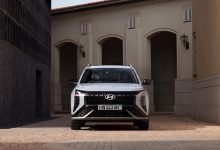 Белый Hyundai Mufasa у здания с арками, вид спереди