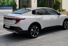 Серебристый Kia K3 сзади сбоку на плитке во дворе здания