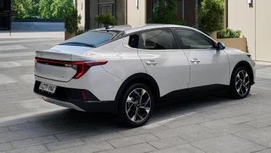 Серебристый Kia K3 сзади сбоку на плитке во дворе здания