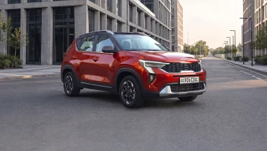Kia Sonet Prime foizsiz muddatli toʻlov va avtokredit - 1 Красный Kia Sonet Prime спереди сбоку на пустой улице между офисными зданиями