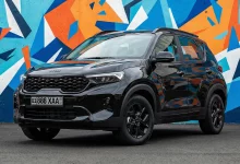Черный Kia Sonet Black Edition спереди сбоку у стены с яркими граффити