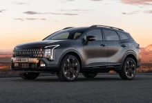Темно-серый обновленный Kia Sportage спереди сбоку на асфальте в пустыне на закате